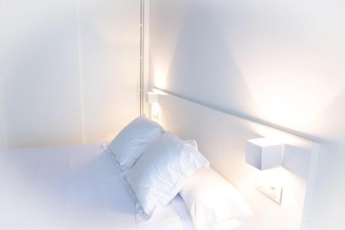 a white room with a bed with two pillows at Hotel Montes in Santiago de Compostela