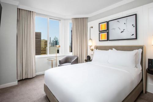a hotel room with a bed and a large window at The Luxury Collection Hotel Manhattan Midtown in New York