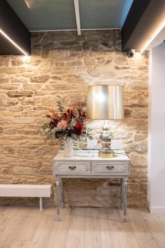 a table with a lamp and flowers on it at Hotel Montes in Santiago de Compostela