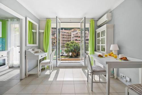 une cuisine avec des rideaux verts, une table et une fenêtre dans l'établissement LE LANDELLE - Centre- Climatisation -Proche Gare SNCF, à Menton