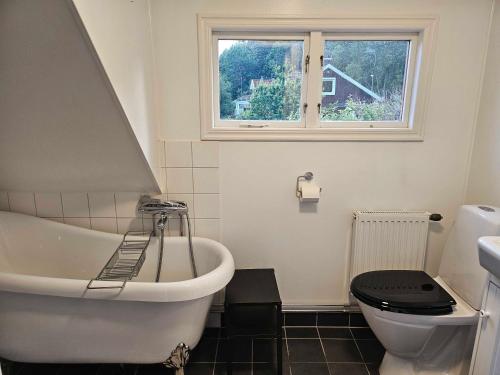 a bathroom with a tub and a toilet and a window at 30-tals villa med närhet till centrala GBG in Gothenburg