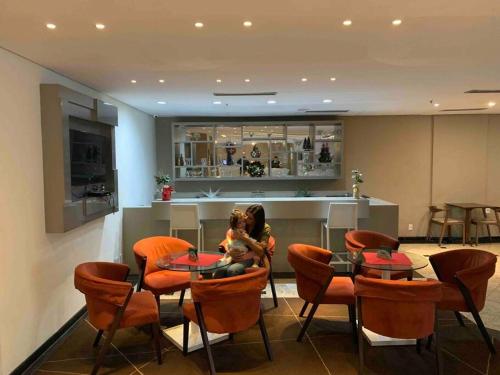 a woman holding a child sitting at a table in a restaurant at Sol Alphaville Flat completo lazer cama casal in Barueri