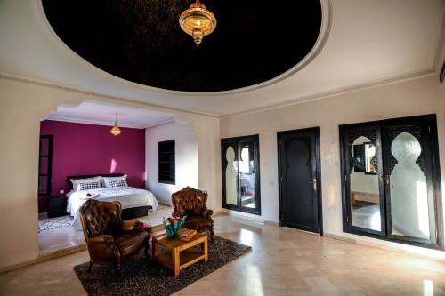 um quarto com uma cama com paredes e cadeiras roxas em Palm satdium em Marrakech