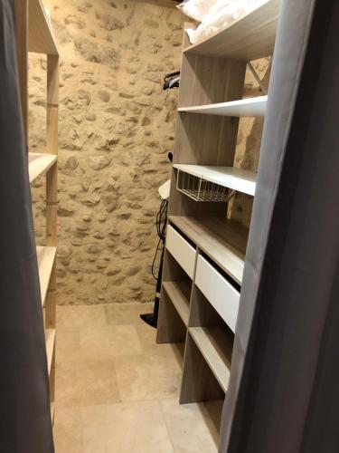 un dressing avec des étagères en bois et un mur en pierre dans l'établissement Le Pesquier, à Roquemaure