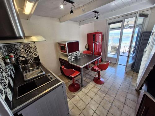 une cuisine avec un comptoir et une table avec des tabourets rouges dans l'établissement Résidence Hawai 1 - Maisonnette studio mezzanine 4 couchages - PORT LEUCATE MAE-7981, à Leucate