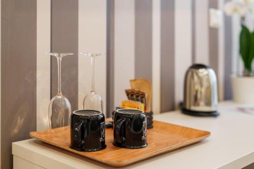 two black coffee mugs on a wooden tray on a counter at It's Room Naples in Naples