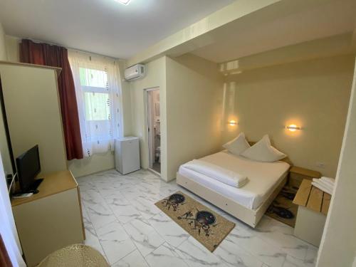 a bedroom with a white bed and a television at Casa Andreea in Eforie Sud
