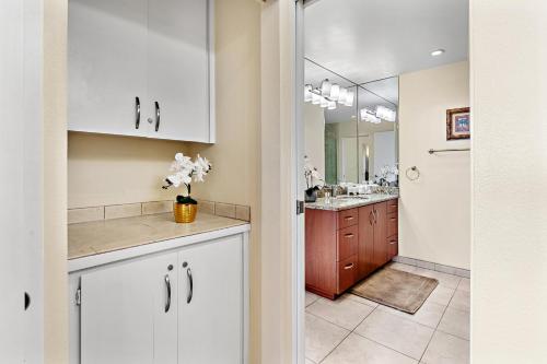 a bathroom with white cabinets and a sink with a mirror at Kapalua Golf Villa 20V 1 in Kahana