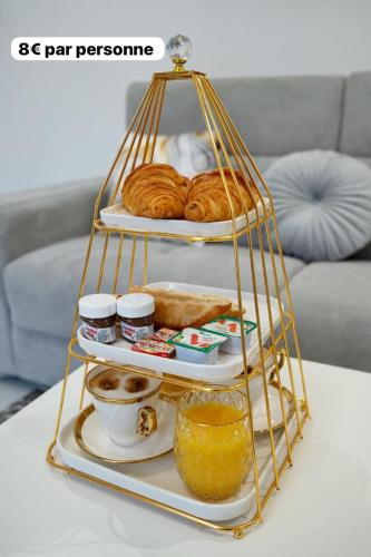 un plateau de service avec des pâtisseries et du pain sur une table dans l'établissement Appartement L'or 2 pièces de 44 m2, à Noisy-le-Sec