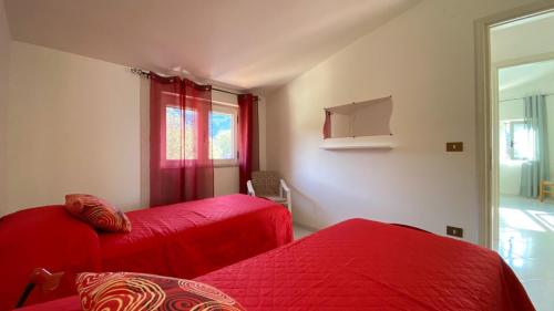 a bedroom with two red beds and a window at Casa Vacanze Angelo in Palinuro