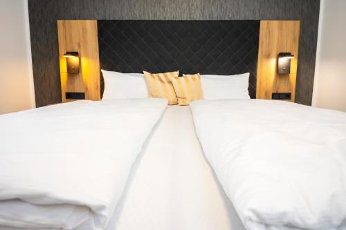 two beds in a hotel room with white sheets and pillows at Hotel am Park Bad Driburg in Bad Driburg
