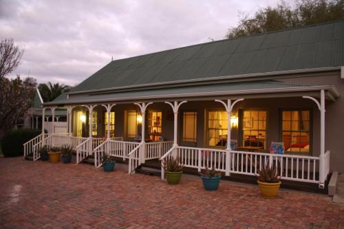 a house with a porch with potted plants at HouseMartin Lodge & Self Catering in De Rust