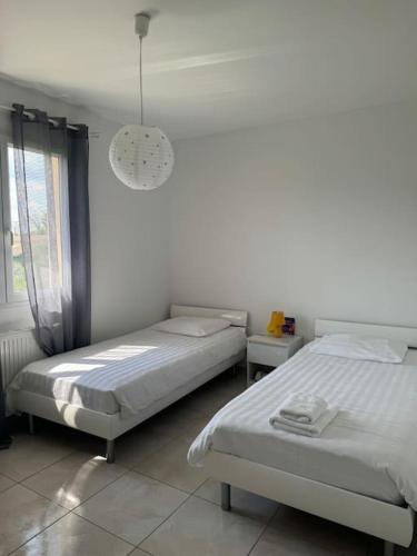 - une chambre avec 2 lits et une lampe pendant dans l'établissement Maison jardin proche lac & Autoroute, à Les Billaux