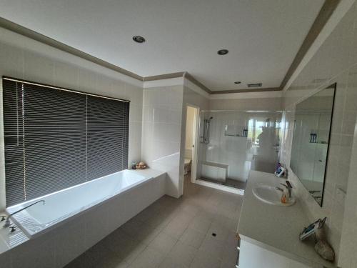a bathroom with a tub and a shower and a sink at Turquoise Coast Lodge in Jurien Bay