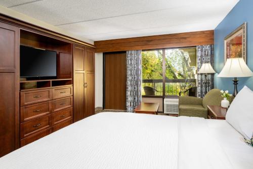 a bedroom with a white bed and a large window at The Inn On The River in Pigeon Forge