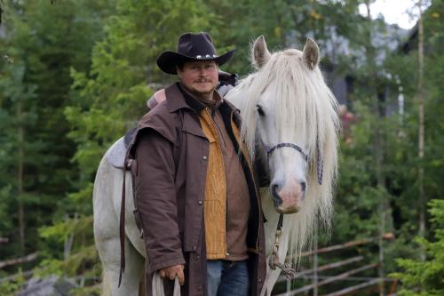a man in a cowboy hat standing next to a white horse at Mountain Lodge in Stöten