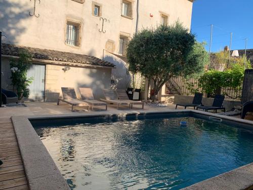 une piscine dans une cour avec des chaises et un bâtiment dans l'établissement Tout Simplement, à Flaux
