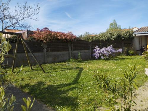a yard with a fence and purple flowers at Chambres dans maison proches Nantes et Vallet in Le Landreau