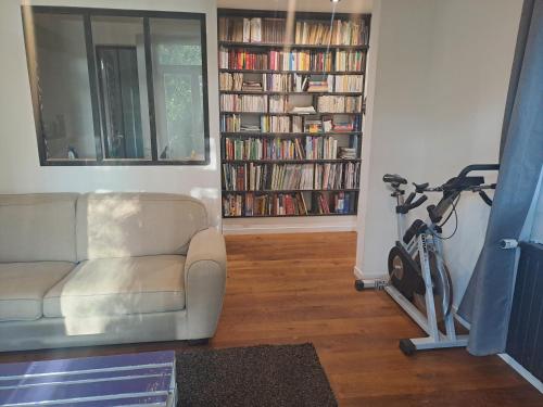 un salon avec un canapé et un vélo à côté d'une étagère dans l'établissement Sous les tilleuls, à Saint-Brévin-les-Pins