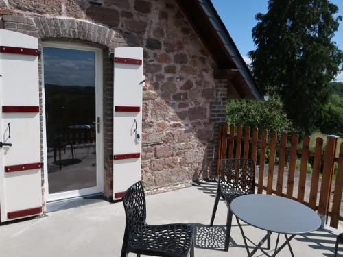d'une terrasse avec une table, des chaises et une porte. dans l'établissement Maison La Chapelle Bellevue, à Saint-Solve