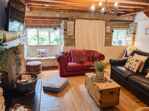 a living room with a red leather couch and a table at Laurel cottage Melplash in Netherbury