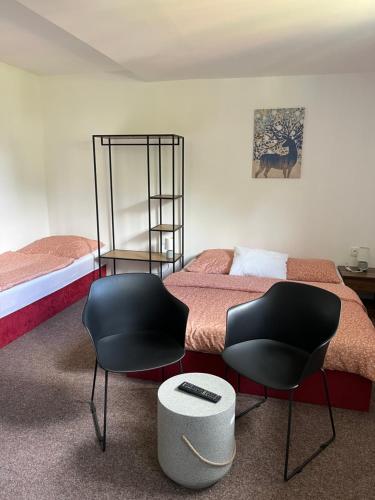 a bedroom with a bed and two black chairs at Apartmány U Šťastných in Cerny Dul