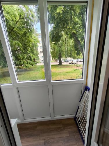 - deux fenêtres dans une chambre avec vue sur un arbre dans l'établissement Tukas Apartment, à Marijampolė