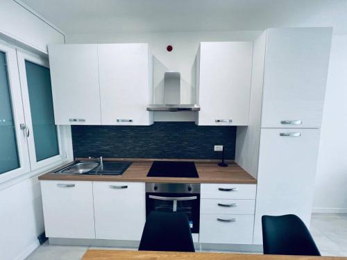 a white kitchen with white cabinets and blue chairs at MK Apartments in Lido di Jesolo