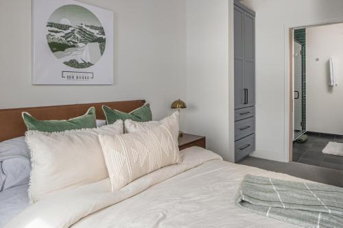 a bedroom with a bed with white sheets and green pillows at Fairways #2 in Big Sky