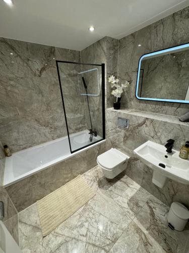 a bathroom with a toilet and a tub and a sink at KM Granton Apartment in Edinburgh