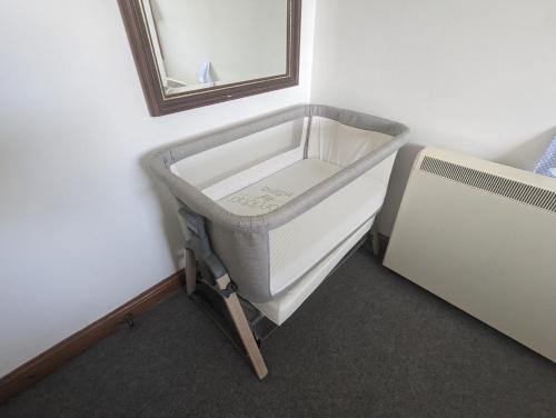 a small bed in a room with a mirror at The Apartment at Chalk House - 3 Beds - 1 Cot in Lindley