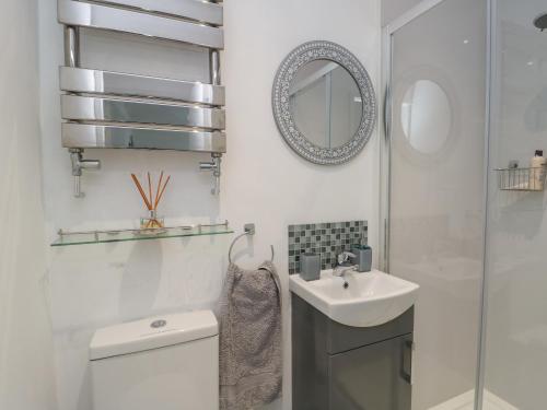 a bathroom with a toilet and a sink and a mirror at Benllech Bay Cottage in Benllech