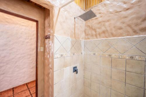 a bathroom with a shower with a tiled wall at BP Surf Hotel in Playa Grande