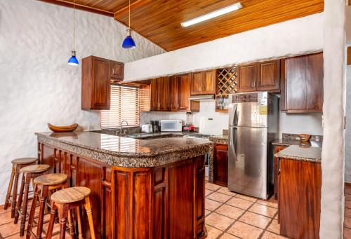 a kitchen with wooden cabinets and a stainless steel refrigerator at BP Surf Hotel in Playa Grande