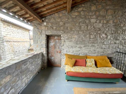 - un canapé dans une chambre dotée d'un mur en pierre dans l'établissement La terrasse suspendue, à Saint Alban Auriolles