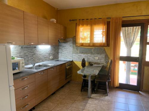 a kitchen with wooden cabinets and a table with a microwave at Villa Isabella in Marina di Grosseto