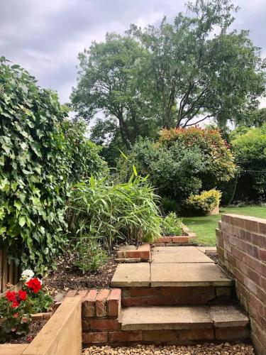 a garden with a brick path and flowers at Linden Suite in Goring