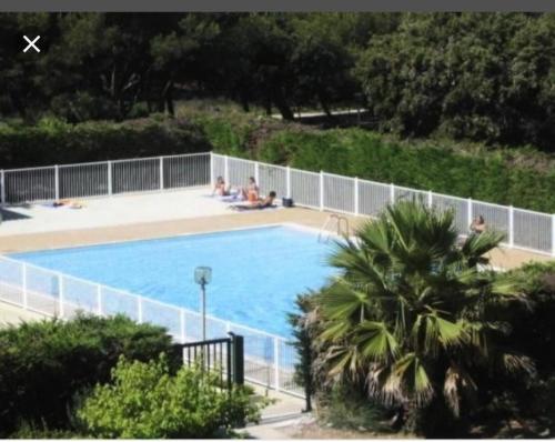 une grande piscine avec des personnes assises autour de celle-ci dans l'établissement Résidence Drakkar - Appartement cosy dans domaine arboré avec piscine et tennis MAE-8711, à Six-Fours-les-Plages