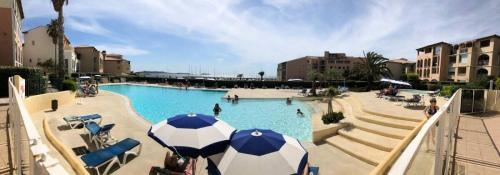 une grande piscine avec un parasol bleu et blanc dans l'établissement Résidence Rivages - Cosy T2 dans le domaine de la Coudoulière pour 5 personnes MAE-6131, à Six-Fours-les-Plages