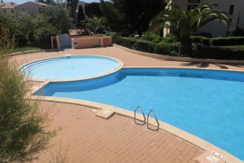une grande piscine bleue sur une passerelle en briques à côté d'un bâtiment dans l'établissement Résidence Jardins D Azur C - T2 avec piscine collective a deux pas de la mer MAE-2631, à Six-Fours-les-Plages