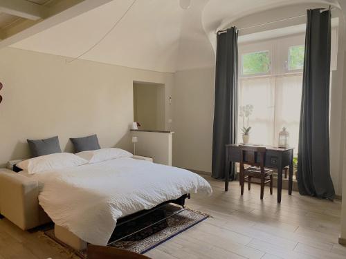 a bedroom with a bed and a desk and a window at Monolocale San Guido in Acqui Terme