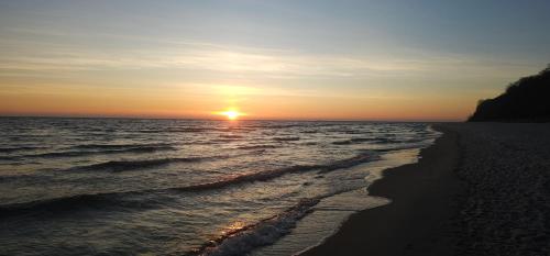 a sunset on a beach with the ocean at Apartament Gdynia Babie Doły in Gdynia