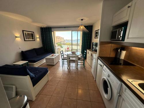 une cuisine et un salon avec un canapé et une table dans l'établissement Résidence Rivages - Cocktail des îles, joli T2 climatisé avec vue sur piscine et mer dans le domaine de la Coudoulière MAE-0521, à Six-Fours-les-Plages