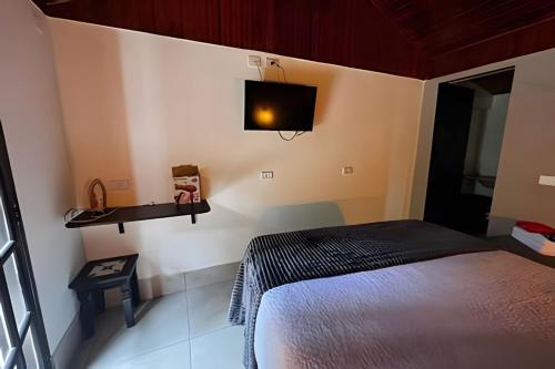 a bedroom with a bed and a tv on the wall at Fracalanza in Campos do Jordão