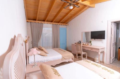 a bedroom with two beds and a desk and a television at Villa Fora Hotel in Alacati