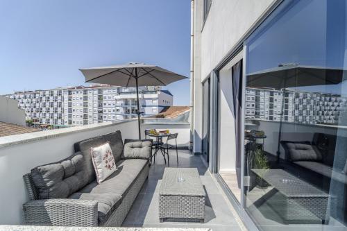 a balcony with a couch and a table and an umbrella at The Locomotive Flat by House and People in Braga