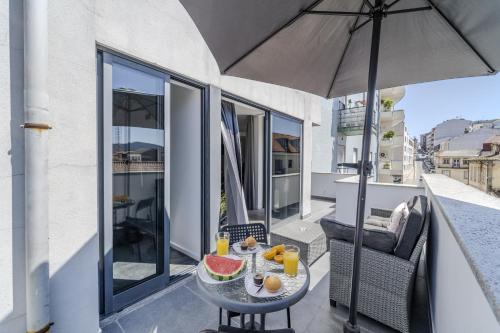 a table with fruit on a balcony with an umbrella at The Locomotive Flat by House and People in Braga