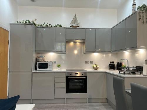 a kitchen with white cabinets and a stove top oven at On the Beach Retreat in Bournemouth
