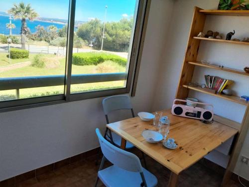 une table en bois avec des chaises et une grande fenêtre dans l'établissement Résidence Marines D'aryana - Appartement 5 couchages proche plage dans résidence avec piscine MAE-3651, à Six-Fours-les-Plages