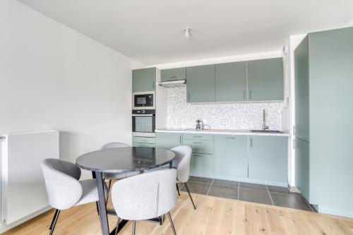 une cuisine avec des armoires blanches et une table et des chaises dans l'établissement C est Votre Maison, à Rueil-Malmaison